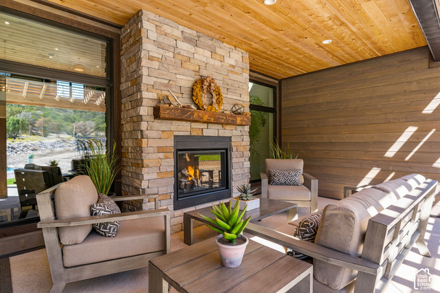 1192 East Ashdown Road Cedar City, UT 84721 - Photo 90 of 96 Covered patio featuring a stone-clad fireplace with a wood mantle, wood-paneled ceiling, and wood-finish wall siding