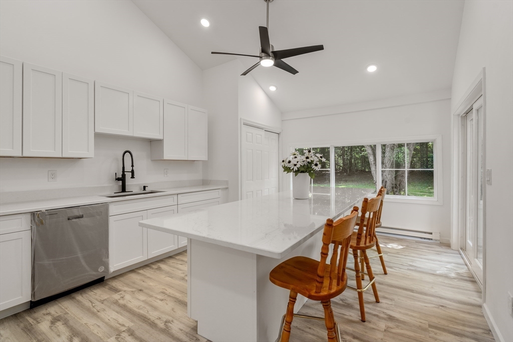 87 Vincent Street Springfield, MA 01129 - Photo 5 of 32 a kitchen with stainless steel appliances kitchen island granite countertop a table chairs in it and wooden floors