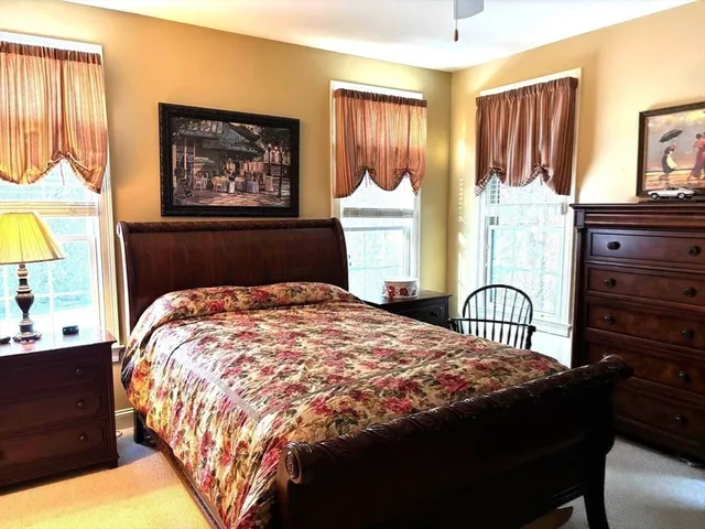 a bedroom with a bed a dresser and painting on the wall