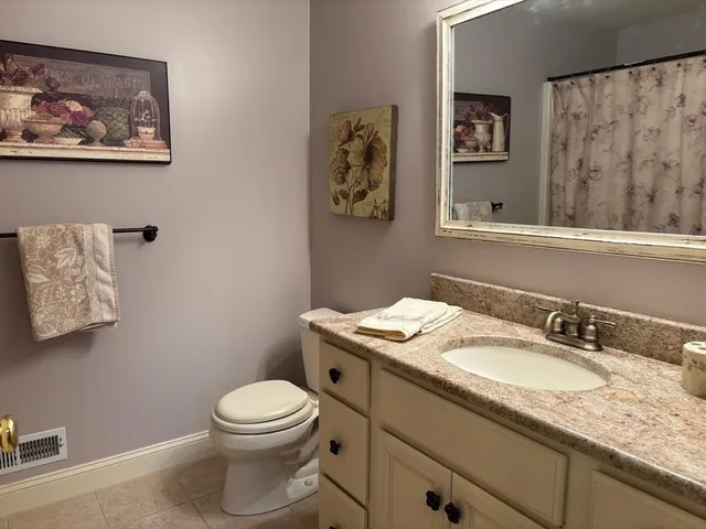 a bathroom with a granite countertop toilet a sink and a mirror