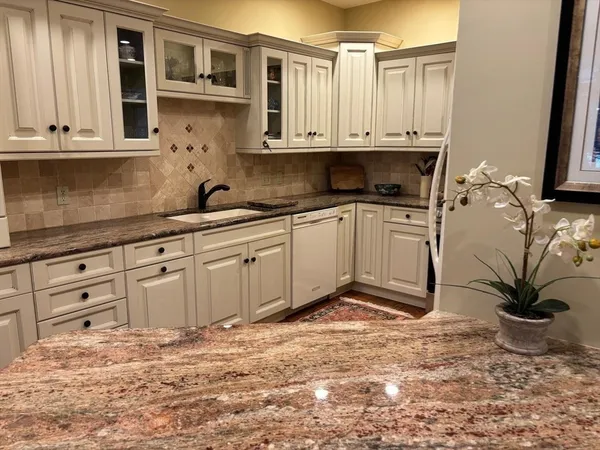 a kitchen with stainless steel appliances granite countertop a stove a sink and a white cabinets