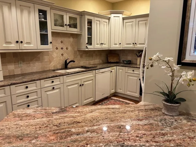 a kitchen with stainless steel appliances granite countertop a stove a sink and a white cabinets