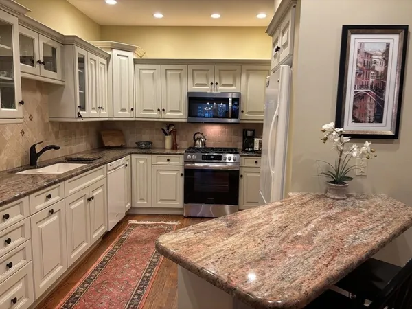a kitchen with kitchen island granite countertop a stove sink and cabinets
