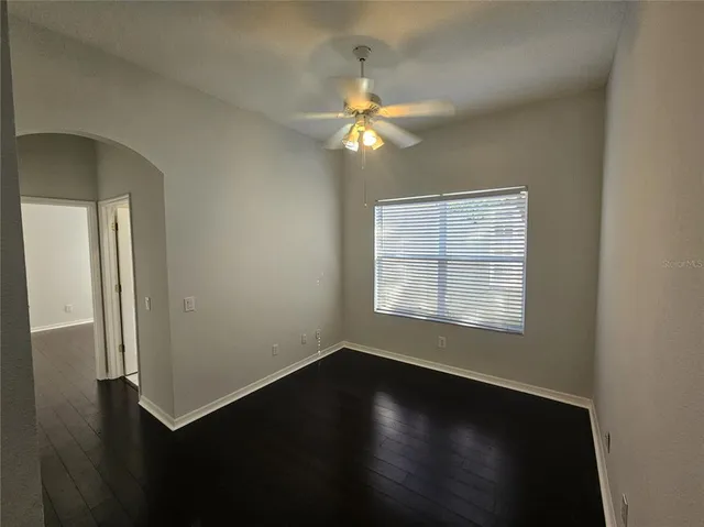 an empty room with wooden floor fan and windows