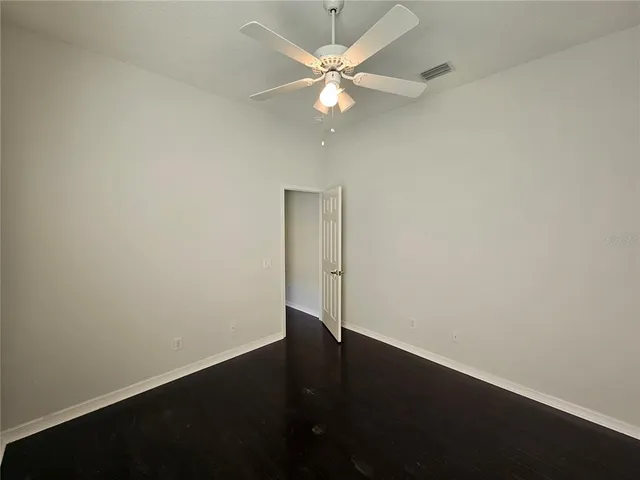 an empty room with a potted plant and a ceiling fan