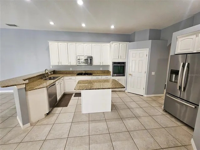 a kitchen with granite countertop a refrigerator sink and cabinets
