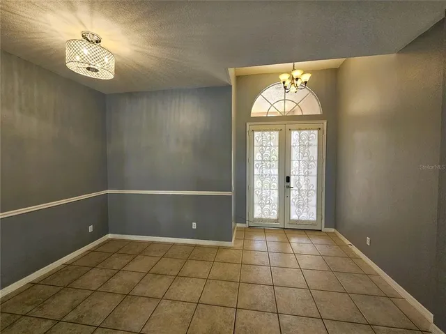 a view of an empty room with window and chandelier fan