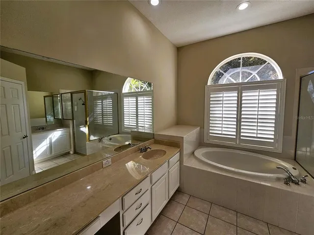 a spacious bathroom with a granite countertop tub a sink and a large mirror