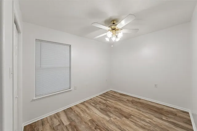 an empty room with a fan & a window