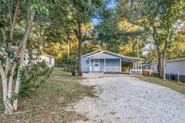 a front view of a house with a dirt yard and a large tree