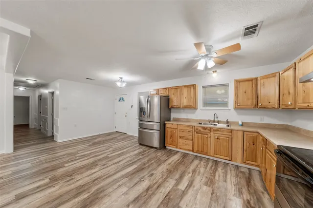 a view of a kitchen with a sink dishwasher a refrigerator and cabinets