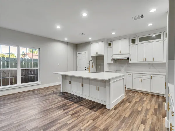 a kitchen with white cabinets and wooden floor