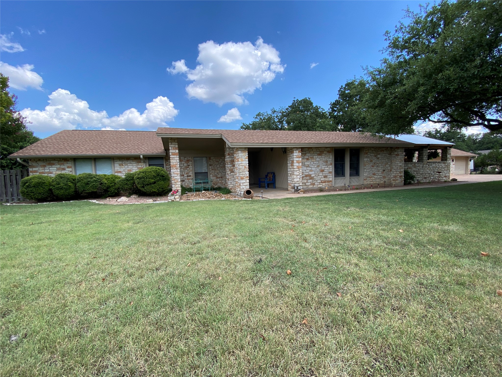 Single story home featuring roof with shingles, a front yard, covered porch, and brick siding