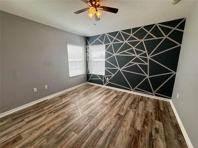 a view of a room with wooden floor and a ceiling fan
