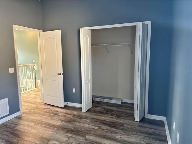 an empty room with wooden floor and closet