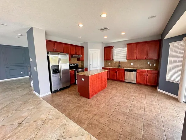 a large kitchen with stainless steel appliances granite countertop a stove refrigerator and cabinets