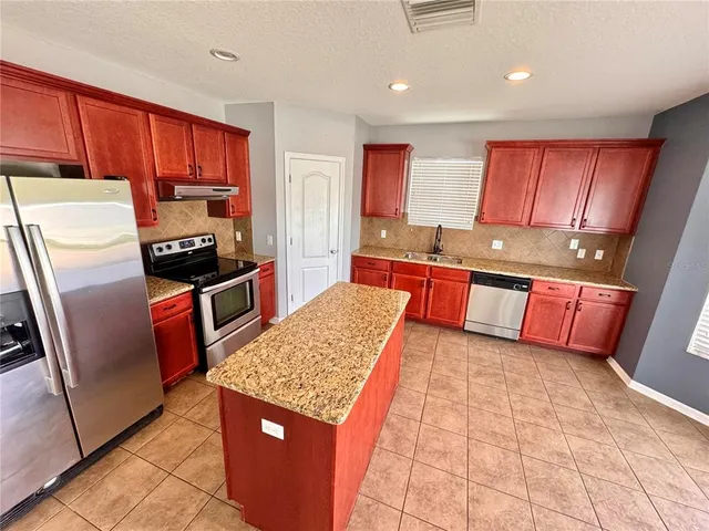 a kitchen with stainless steel appliances granite countertop a refrigerator and a stove