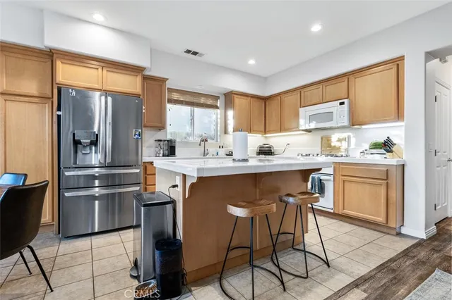 a kitchen with stainless steel appliances kitchen island granite countertop a refrigerator a stove a sink dishwasher and white cabinets with wooden floor