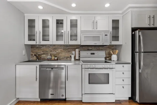 a kitchen with cabinets stainless steel appliances and wooden floor