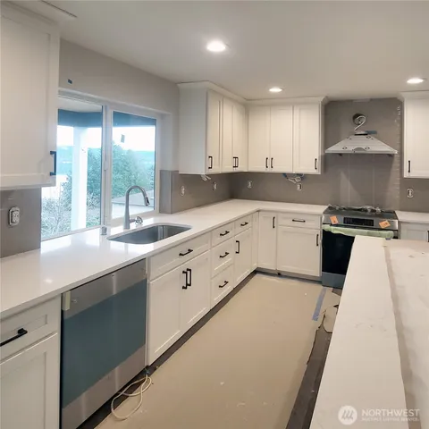 a kitchen with a stove a sink a microwave a counter top space and cabinets