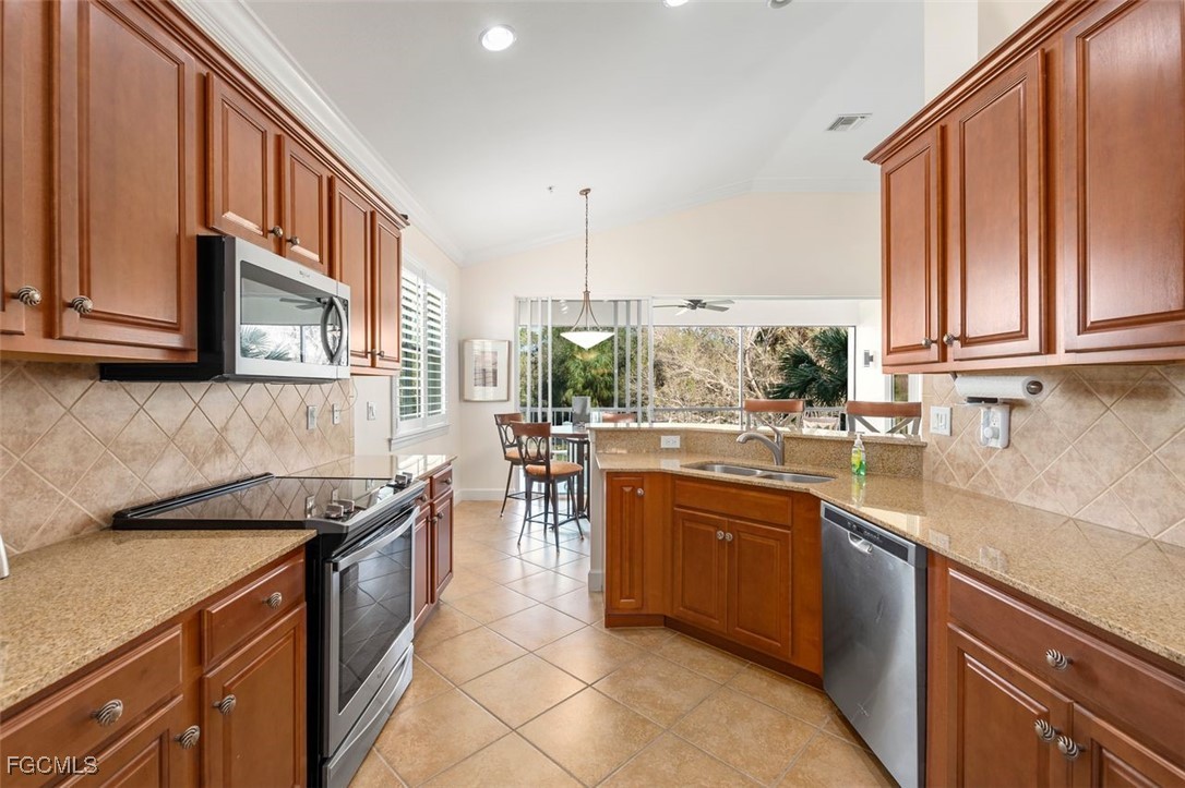13071 Pebblebrook Point Circle, Unit 201 Fort Myers, FL 33905 - Photo 12 of 41 a kitchen with stainless steel appliances granite countertop a sink a stove and a wooden cabinets