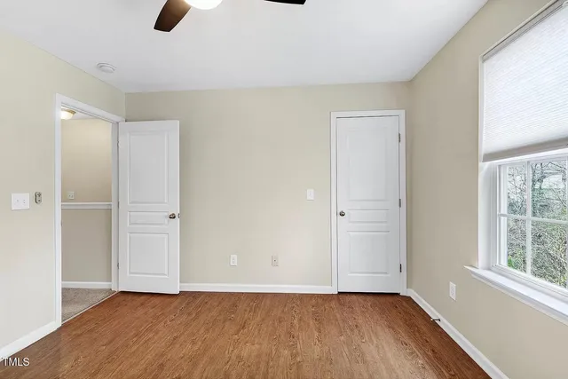 an empty room with wooden floor cabinet and windows