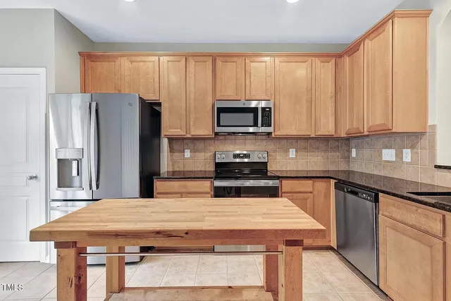 a kitchen with a stove a microwave a refrigerator a sink and cabinets