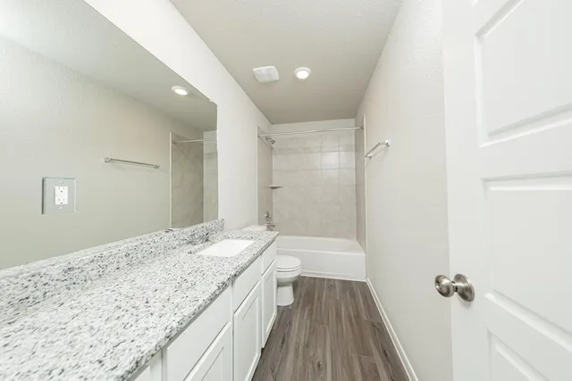 a bathroom with a granite countertop sink a toilet and shower