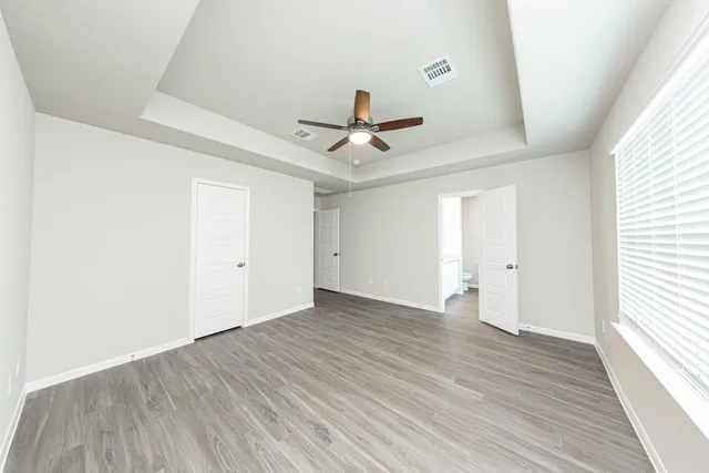 an empty room with wooden floor and ceiling fan