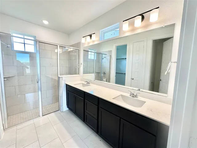 a bathroom with a double vanity sink mirror and shower