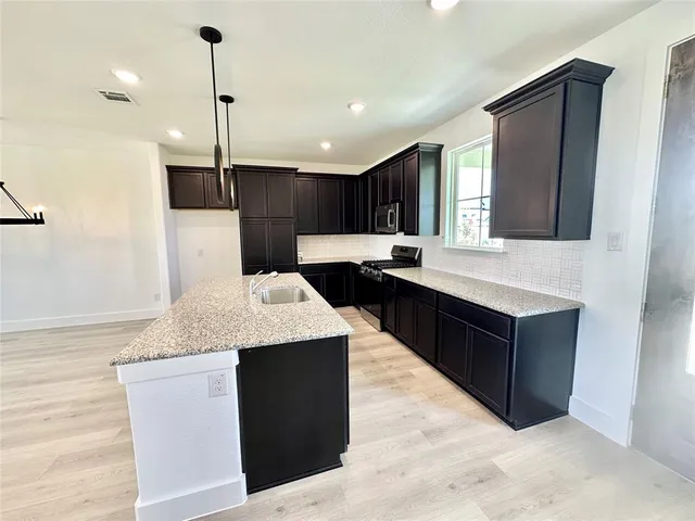 a kitchen with kitchen island granite countertop a sink a counter top space appliances and cabinets