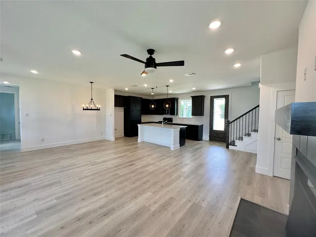 a large kitchen with stainless steel appliances granite countertop a large center island a stove a refrigerator cabinets and living room view