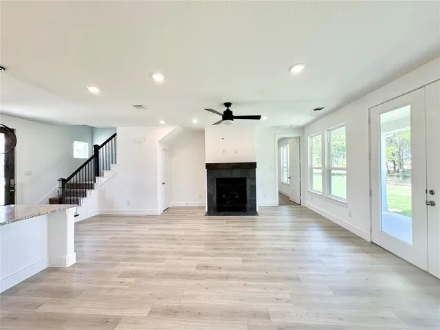 an empty room with wooden floor fireplace and windows