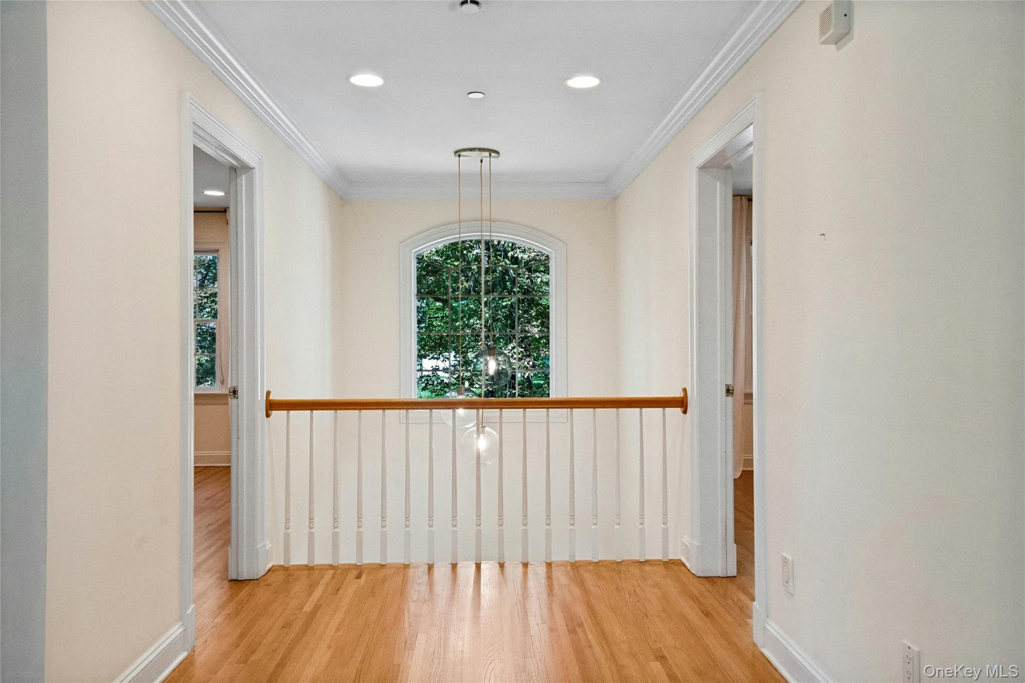 25 Riverview Road Irvington, NY 10533 - Photo 18 of 41 Balcony over looking the living room on one side and the foyer on the other. Hardwood flooring, crown molding, recessed lighting, arched window, and a wood railing