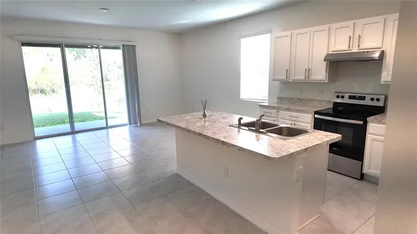 a kitchen with granite countertop a sink a stove and cabinets