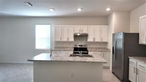 a kitchen with kitchen island a counter top space a refrigerator and a sink