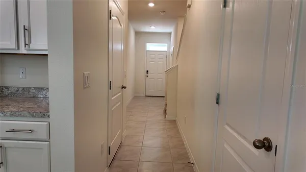 a view of a hallway with granite countertop white cabinets and a sink