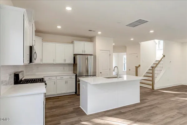 a kitchen with stainless steel appliances granite countertop a refrigerator a sink and a stove