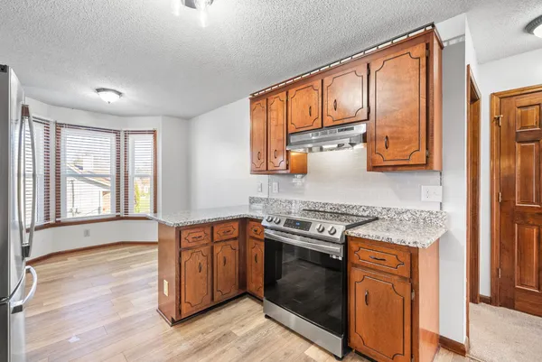 a kitchen with stainless steel appliances granite countertop wooden cabinets stove top oven and sink