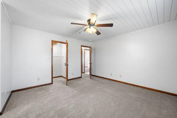an empty room with closet and a chandelier fan