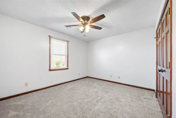 an empty room with ceiling fan and window