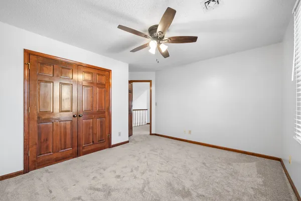 an empty room with a ceiling fan and window