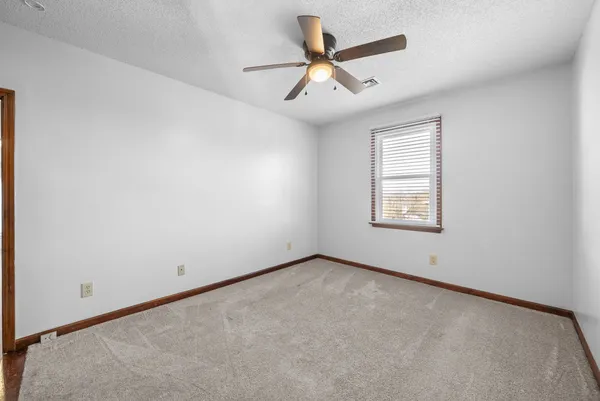 an empty room with ceiling fan and window