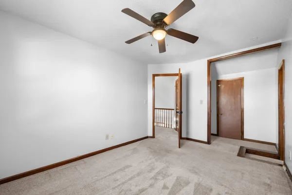 an empty room with a ceiling fan and carpet