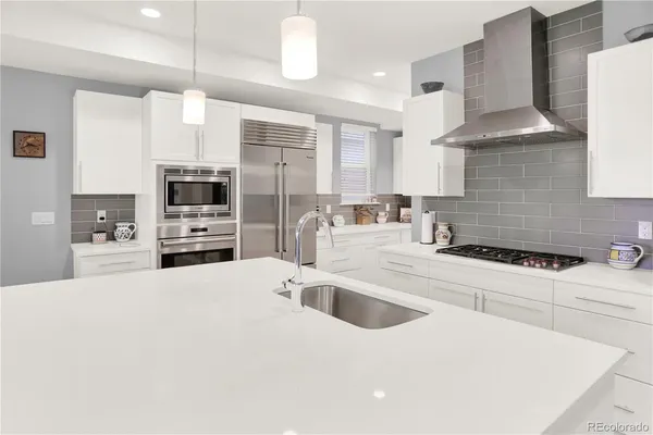 a kitchen with stainless steel appliances kitchen island granite countertop a sink a stove and a refrigerator