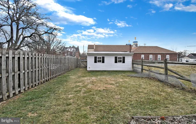 a view of a house with a small yard and a large tree