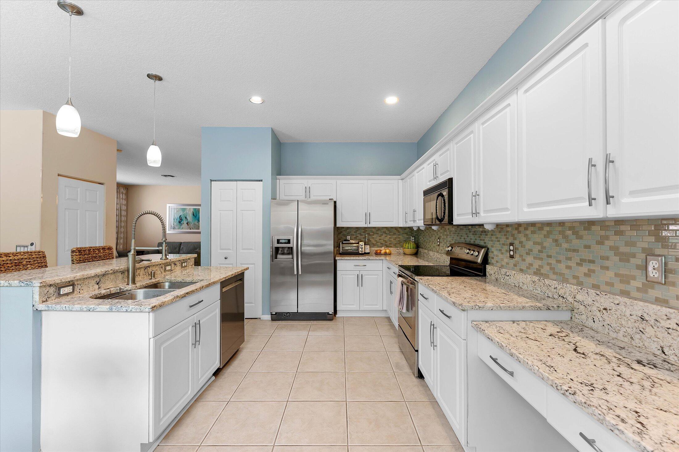 7061 Chesapeake Circle Boynton Beach, FL 33436 - Photo 11 of 51 a large kitchen with a stove top oven a sink a counter space and cabinets