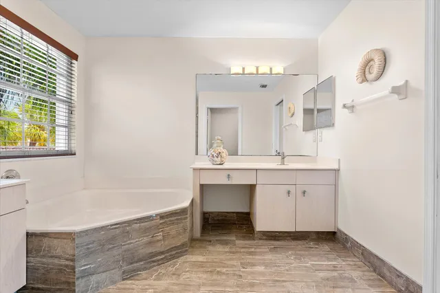 a spacious bathroom with a tub sink and mirror