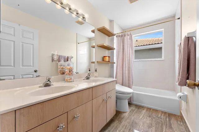 a bathroom with a double vanity sink toilet and shower