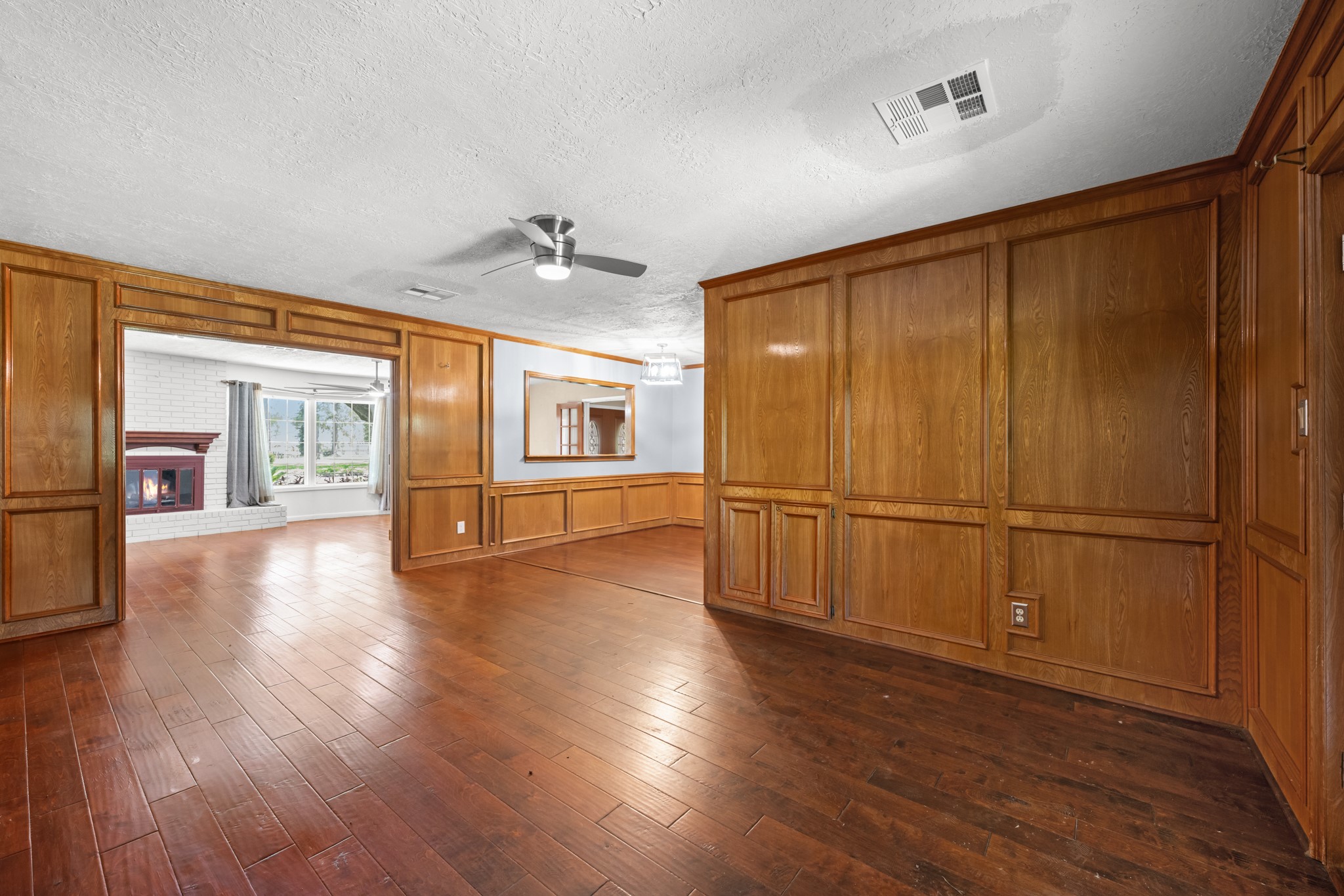 616 Cannan Drive Angleton, TX 77515 - Photo 8 of 49 Rich wood paneling, custom built-in cabinetry, and elegant wainscoting give this formal living area timeless character and warmth. The spacious layout flows seamlessly into the family room and dining areas, creating an inviting setting for holiday gatherings, dinner parties, and everyday entertaining.